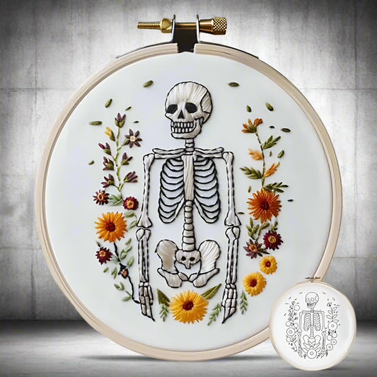 Embroidery hoop with skeleton and floral design on a white background