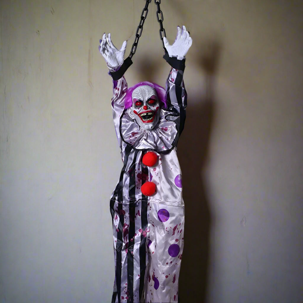 Hanging clown decoration with a white face, red balls, and purple polka dots on a white background