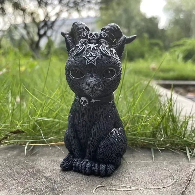 Black cat figurine with decorative headgear on a grassy background