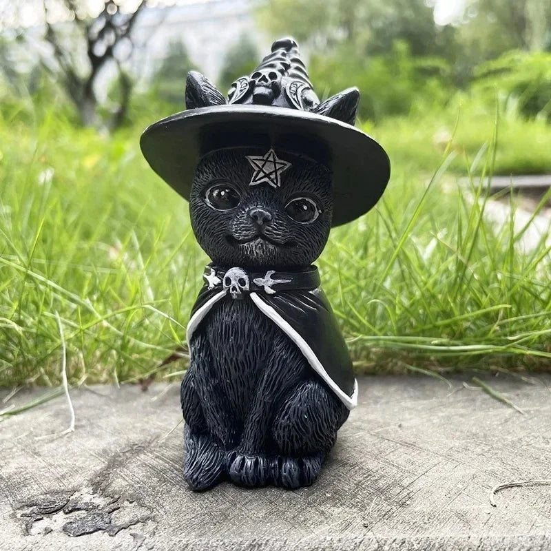 Black cat figurine wearing a witch hat with skull designs on a grassy background