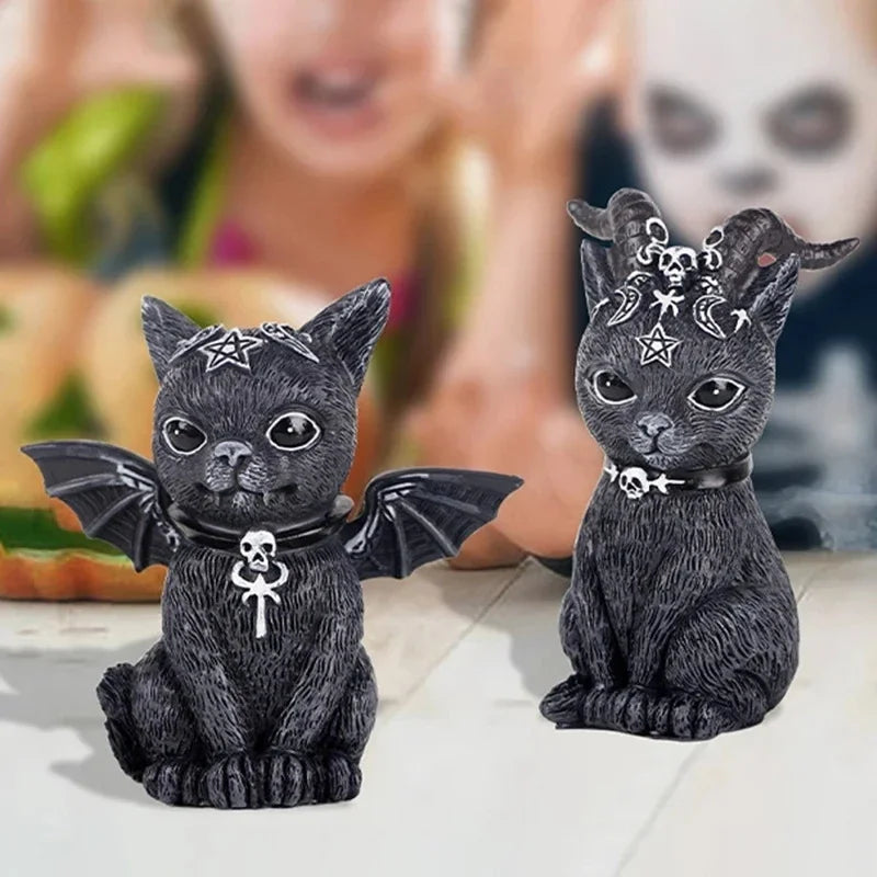 Two black cat figurines with decorative collars and accessories on a blurred background.