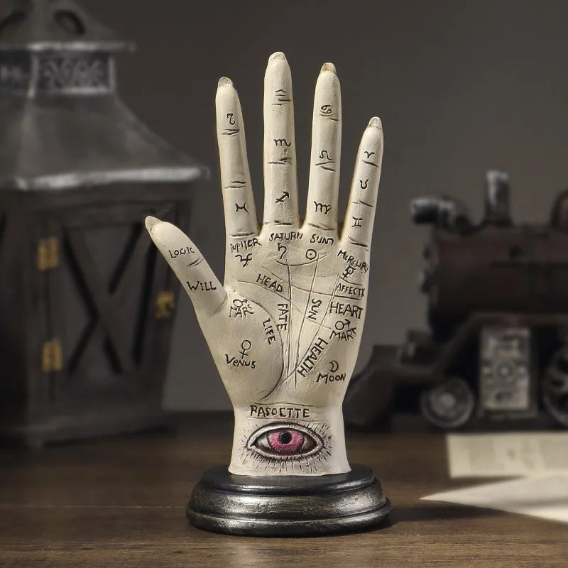 Decorative hand model with palmistry lines and an eye on a wooden surface.
