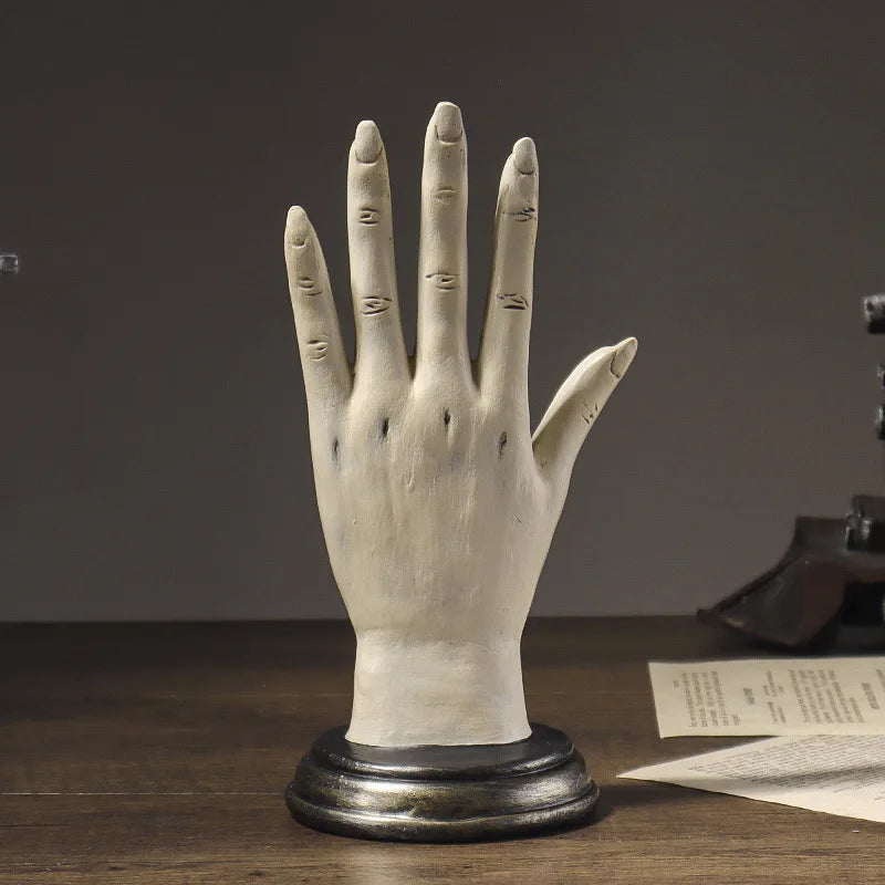 Vintage-style hand sculpture on a wooden base with a dark background