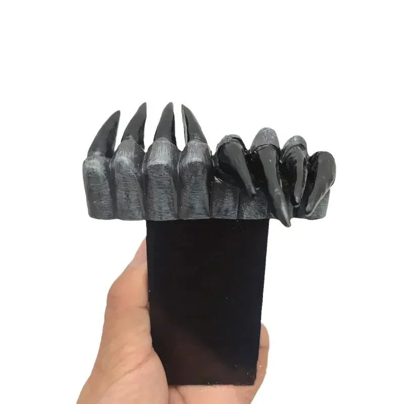 Black and gray claw-like object held in a hand against a white background