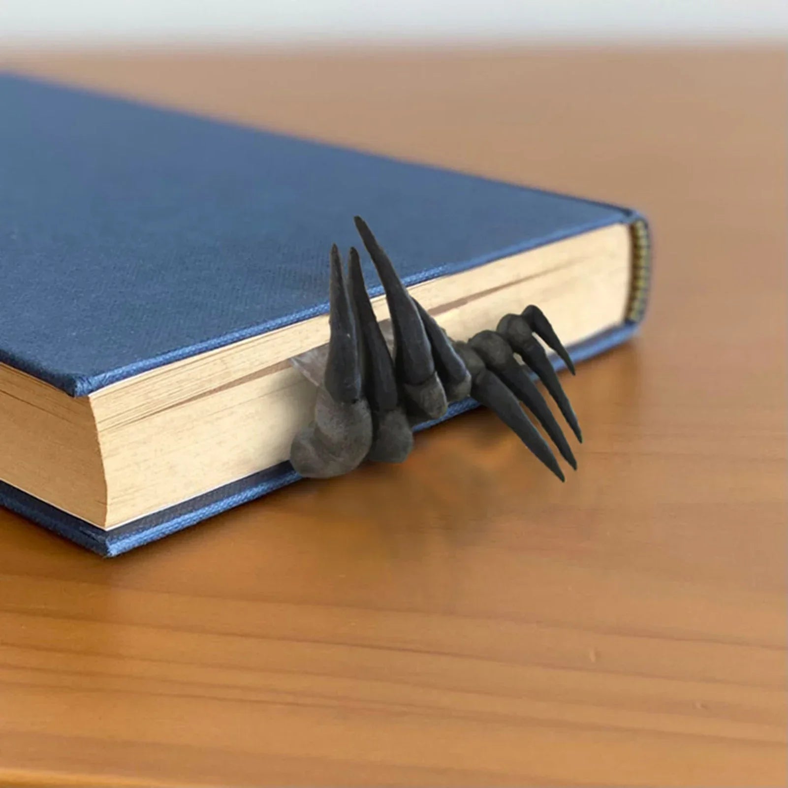 Black claw-like object on a blue book on a wooden surface