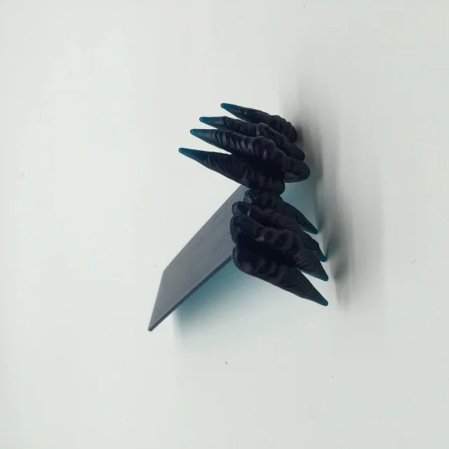 Black decorative item with pointed ends on a white background