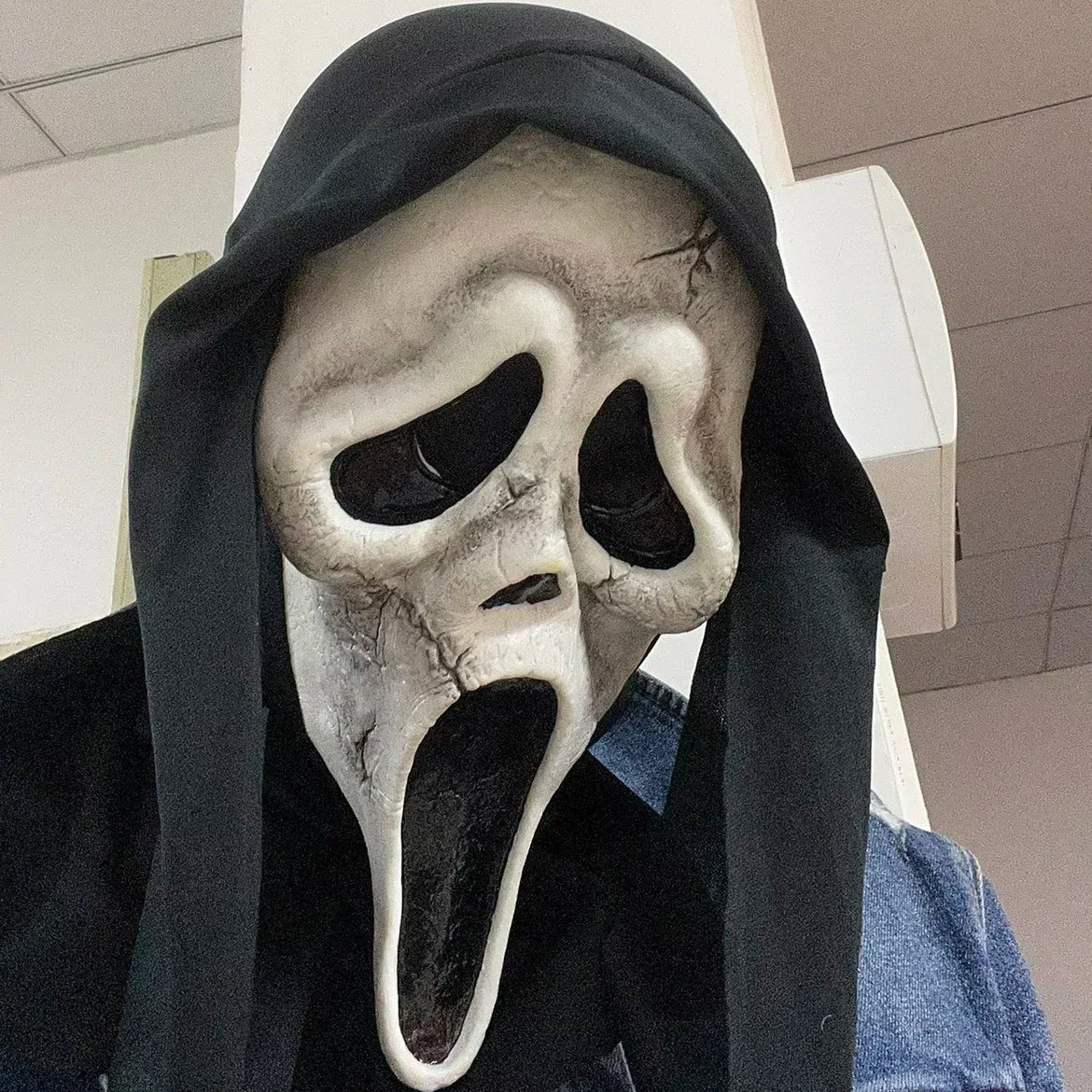Person wearing a ghost face mask in an indoor setting