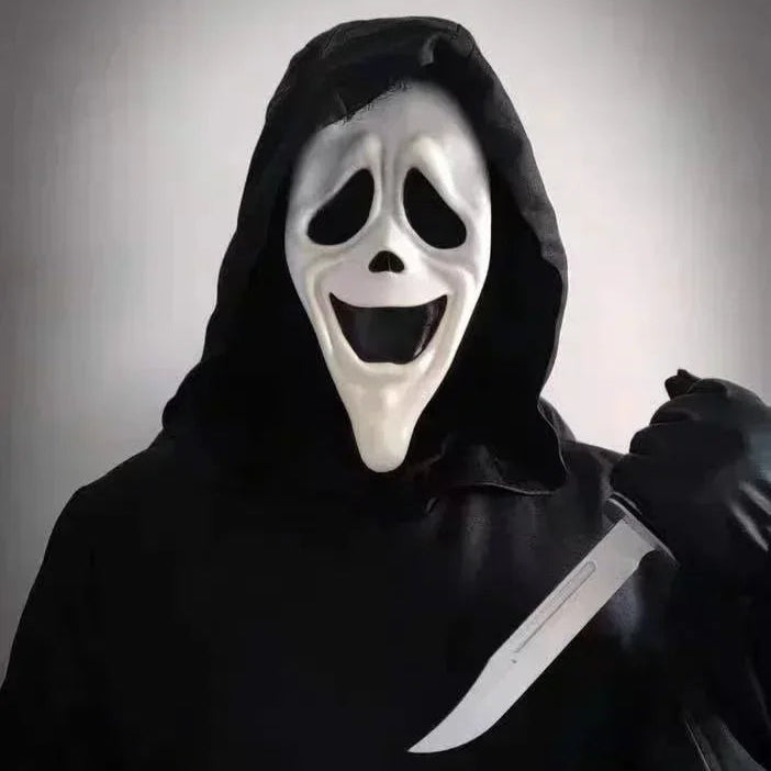 Person wearing a black hooded outfit with a white mask and holding a knife against a gray background
