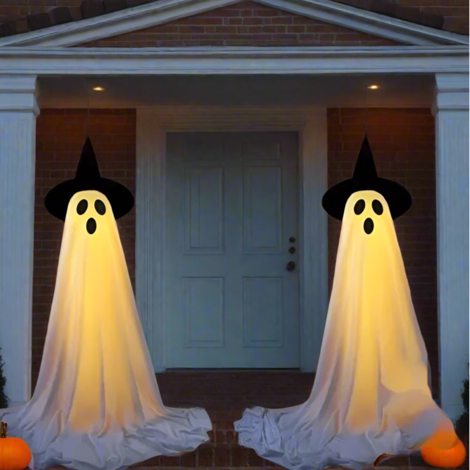 Two ghost decorations in front of a door with Halloween pumpkins and lights.