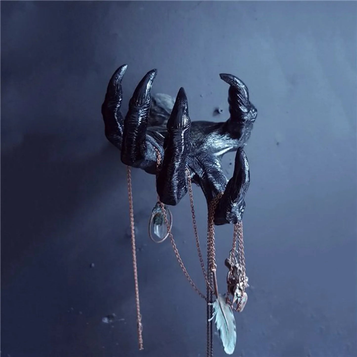 Decorative wall hook with claw design and hanging jewelry on a dark background