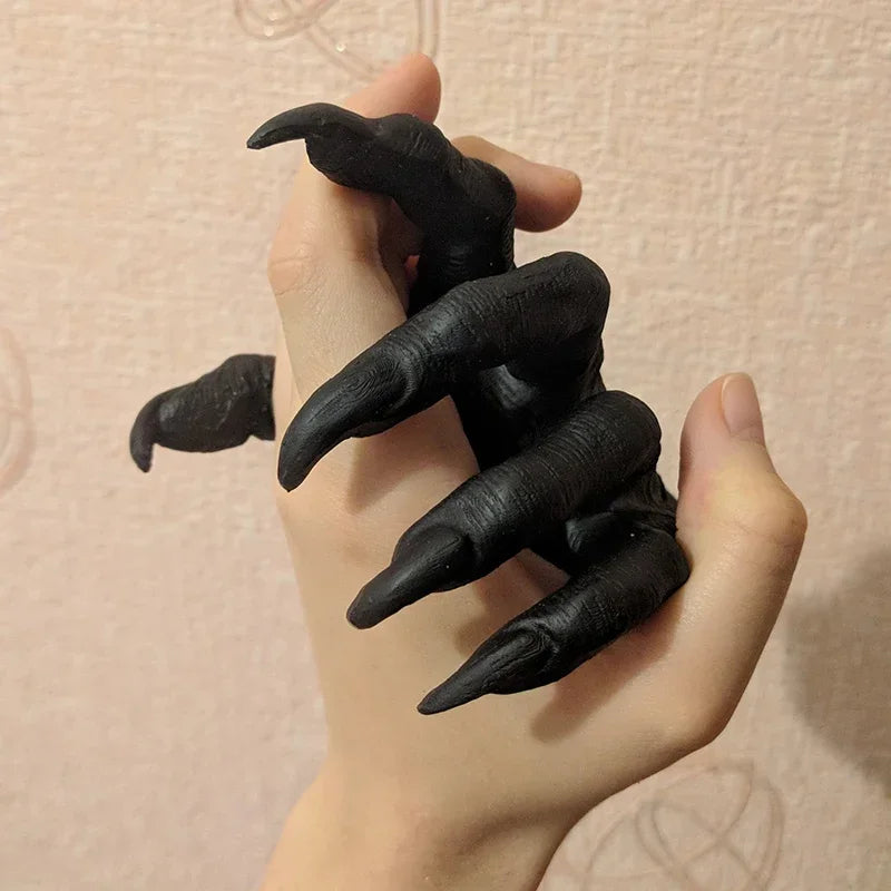 Black claw-like finger extensions worn on a hand against a beige background