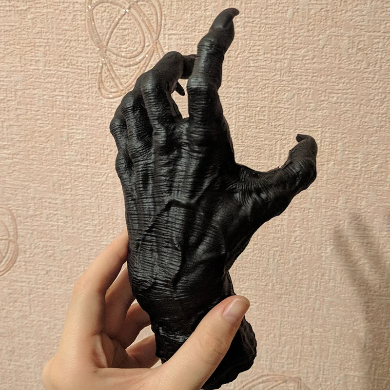 Black hand sculpture held by a person against a beige background