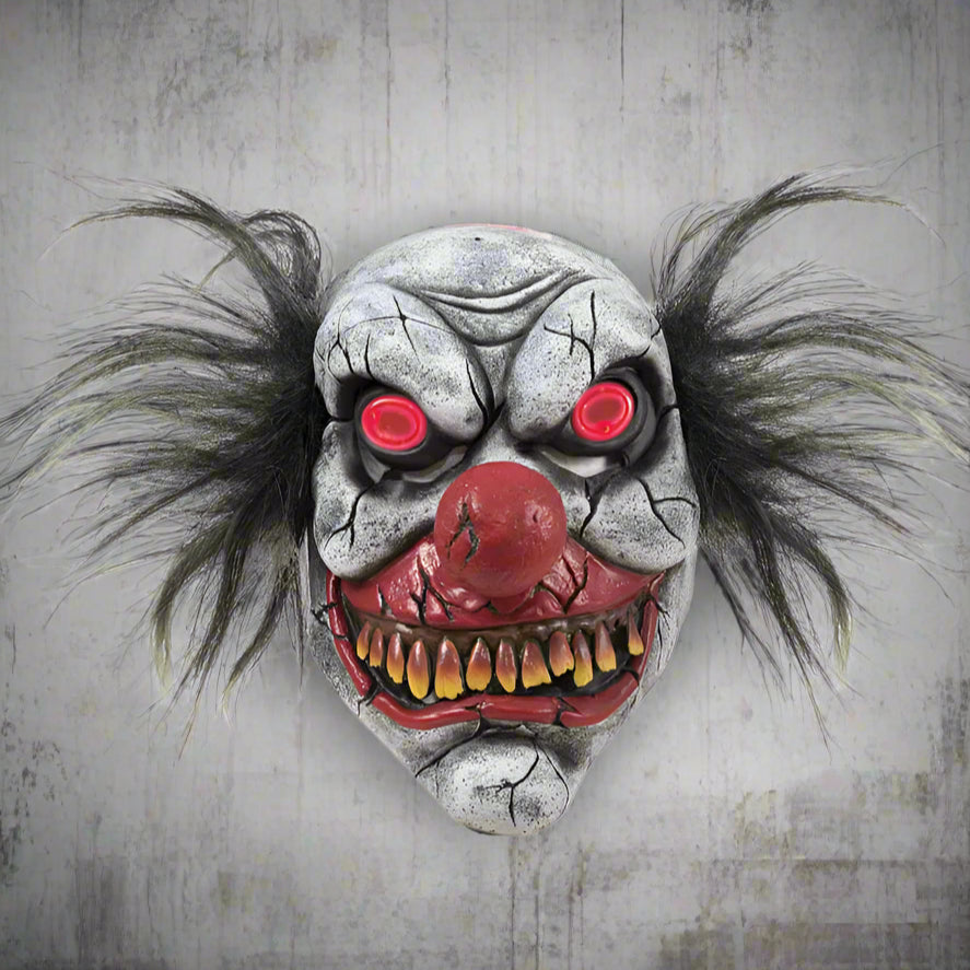 Scary clown mask with red eyes and open mouth on a white background