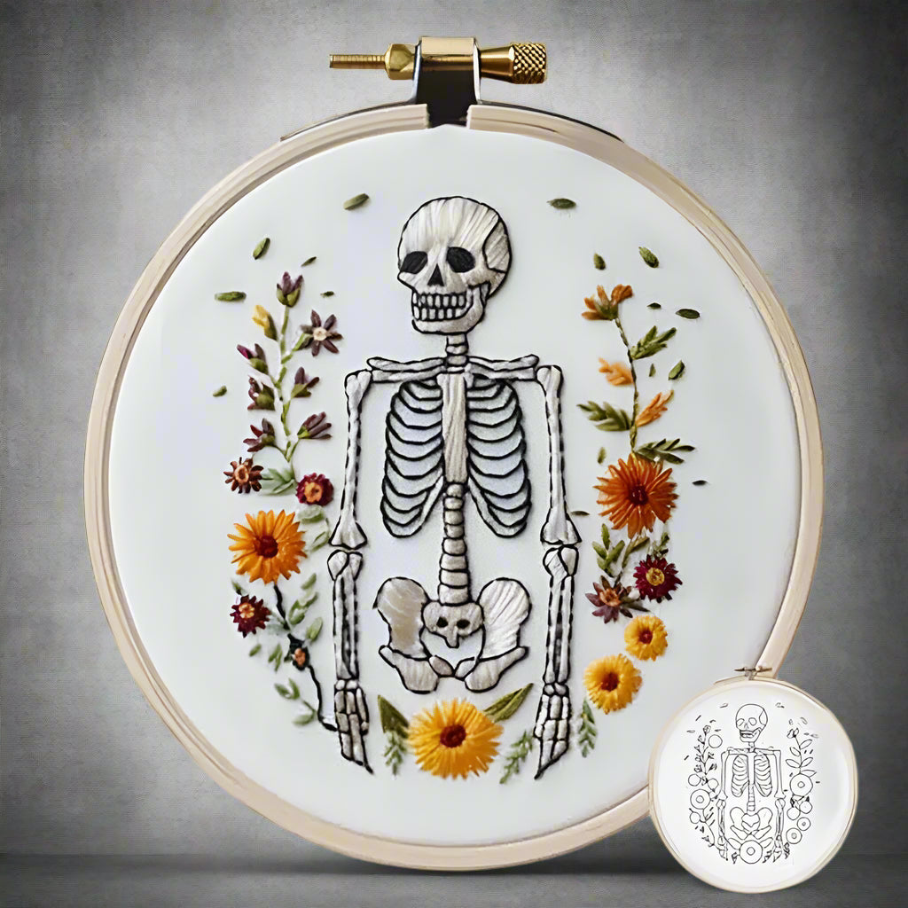 Embroidery hoop with a skeleton and floral design on a white background