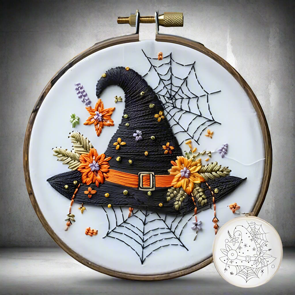 Embroidery hoop with a Halloween-themed design featuring a witch's hat, flowers, and spider webs.