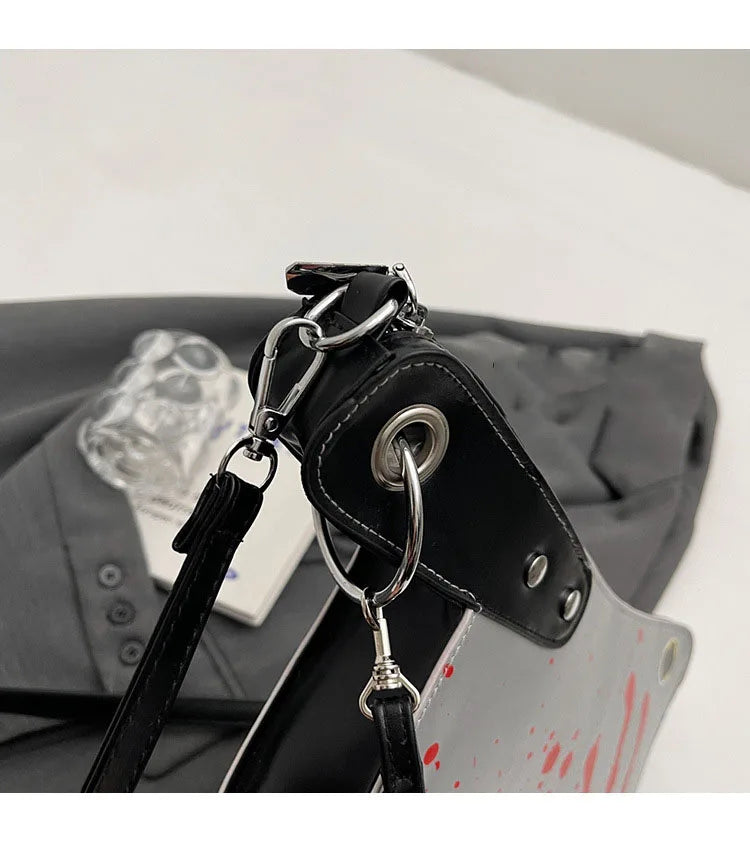 Close-up of a black leather bag with a strap and metal clasp on a gray surface.