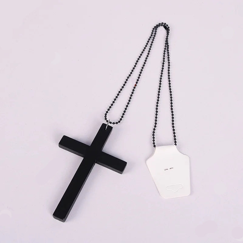 Black cross pendant with a chain on a light pink background