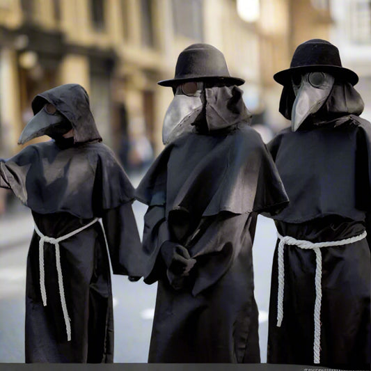 Three people dressed in black plague doctor costumes outdoors.