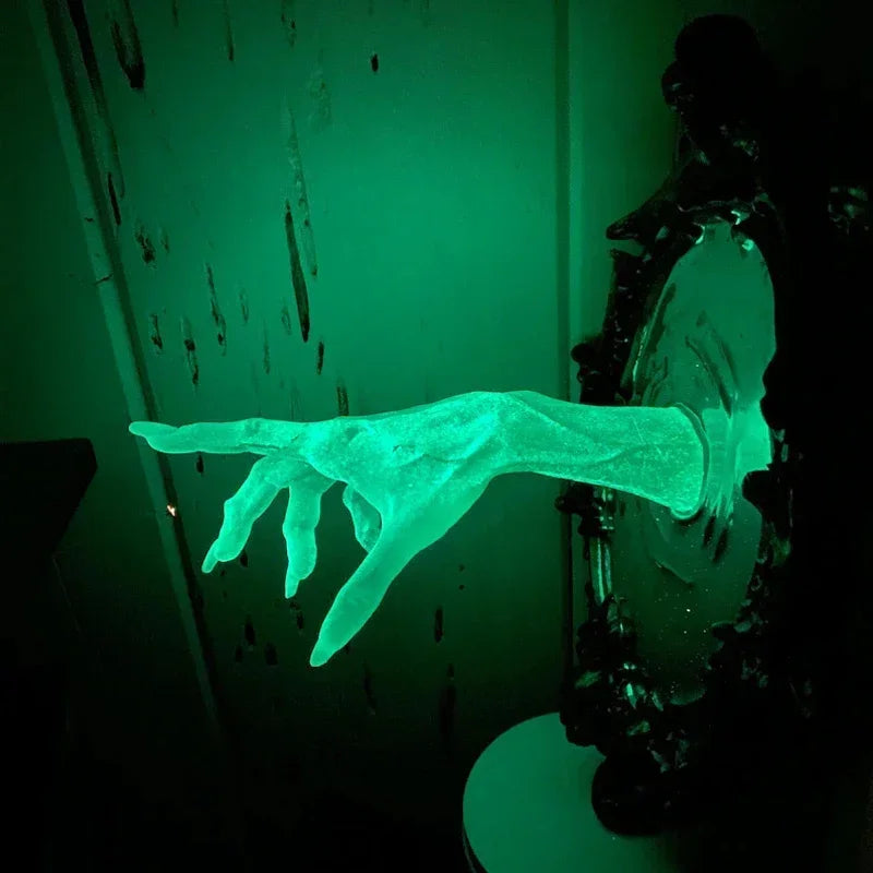 Glowing green hand reaching out from a dark, textured surface
