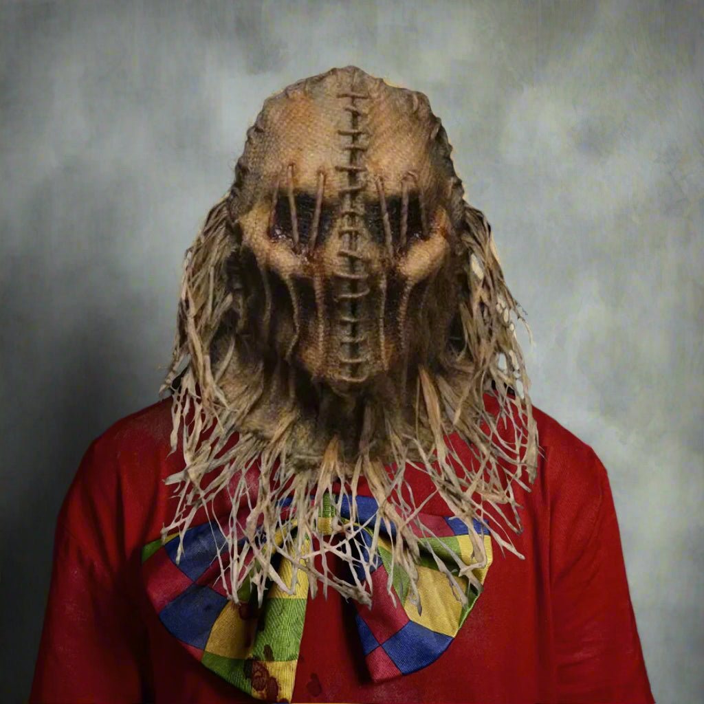 Person wearing a detailed mask with a red shirt and colorful scarf against a black background