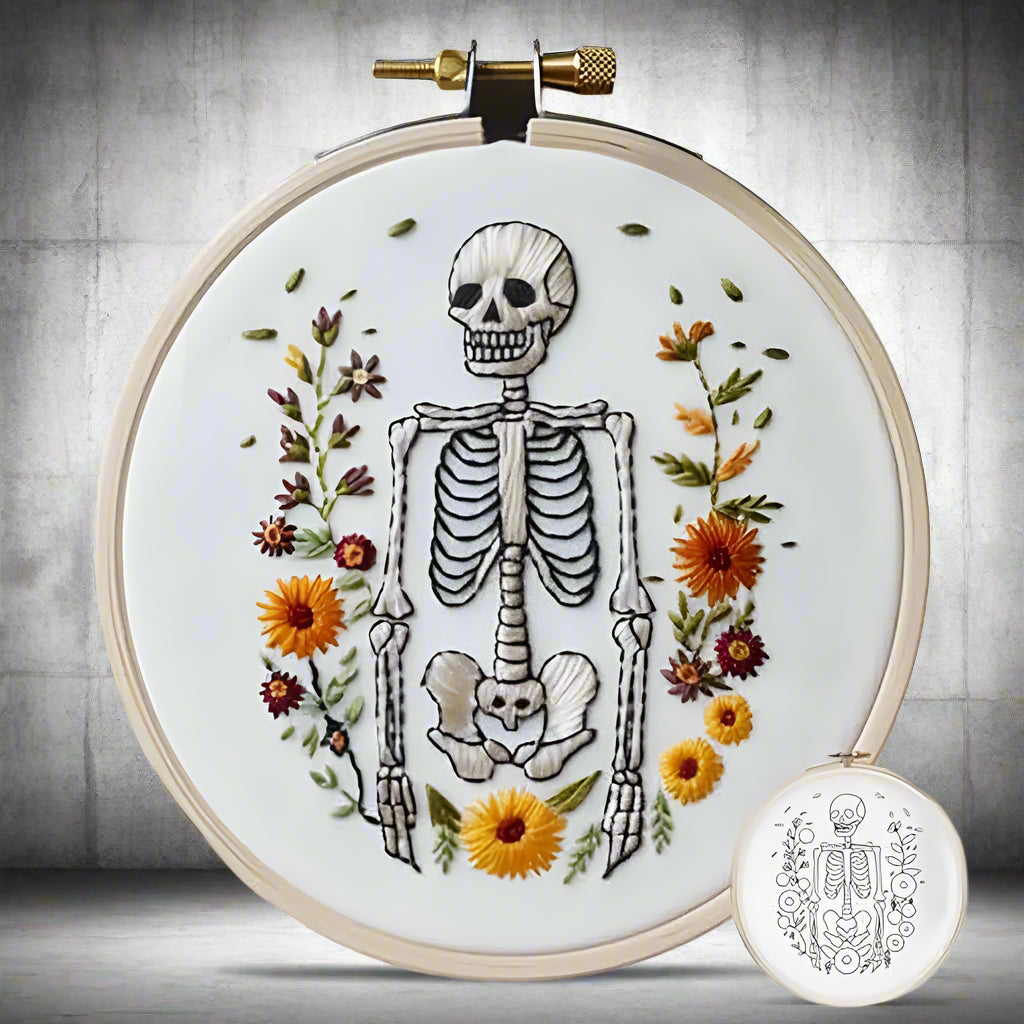 Embroidery hoop with skeleton and floral design on a white background