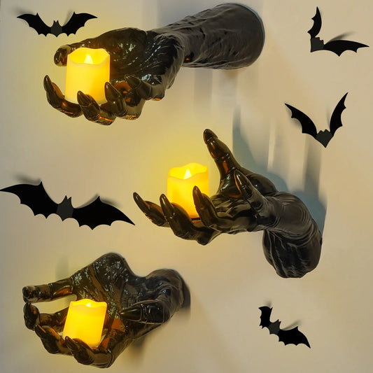 Decorative wall art with hands holding candles and black bats on a light background