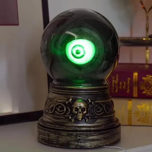 Decorative crystal ball with green light on a skull-themed base