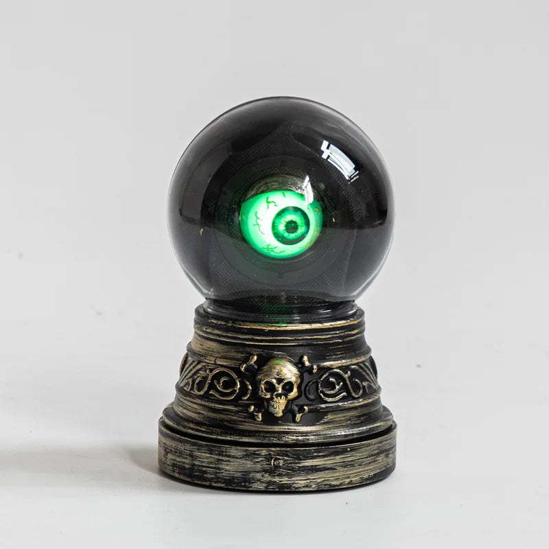 Decorative object with a black sphere containing a green eye and skull design on a gray background