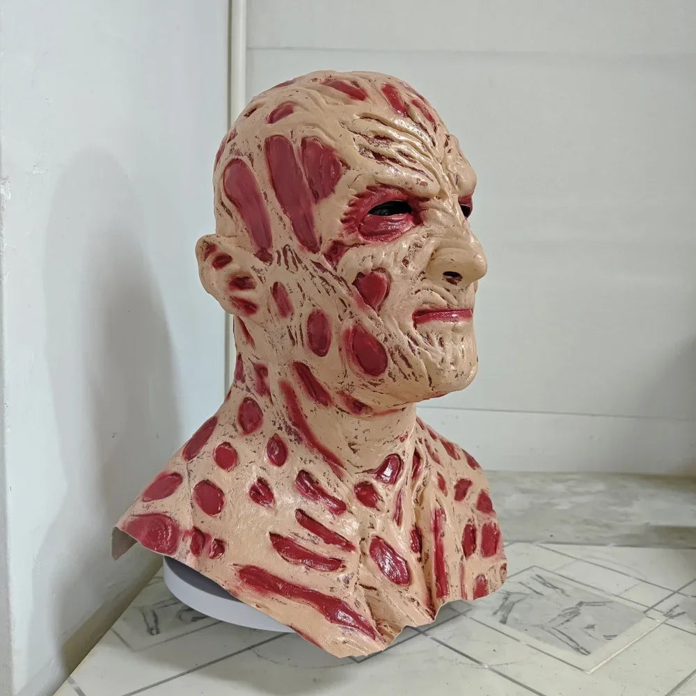Bizarre mask with red and beige texture on a white floor.