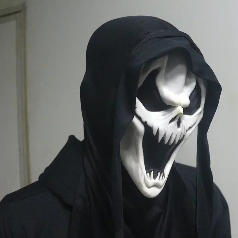 Person wearing a black hooded garment with a white skull mask against a plain background