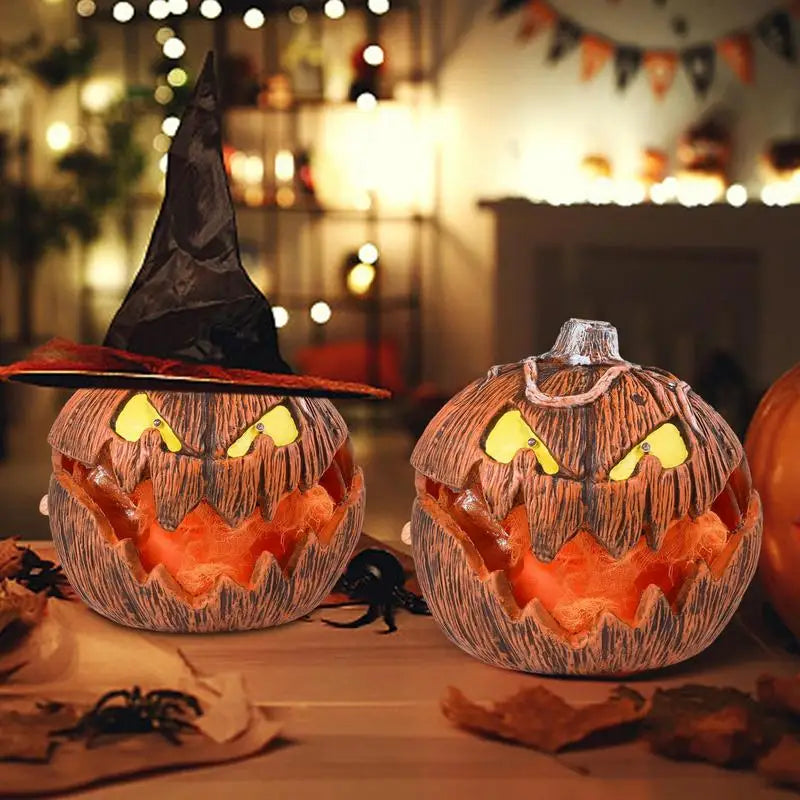 Two Halloween-themed pumpkins with carved faces and a witch hat on a table.