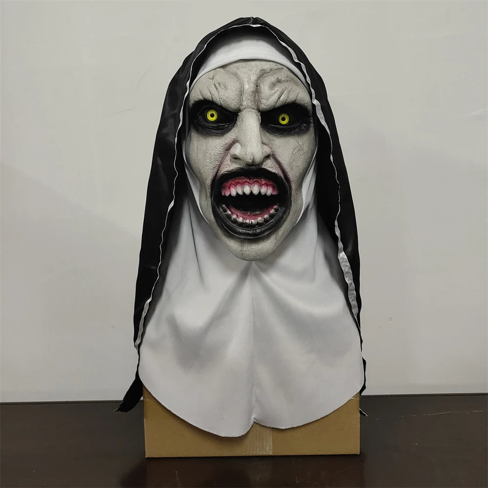 Horror-themed mask with white face and black hood on a cardboard stand against a plain background