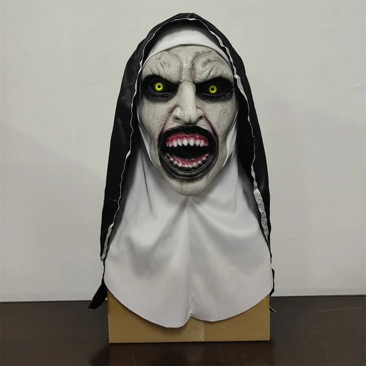 Horror-themed mask with white face and black hood on a cardboard stand against a plain background