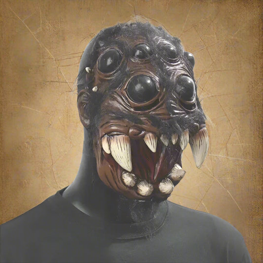 Person wearing a detailed animal mask with large eyes and sharp teeth on a plain background
