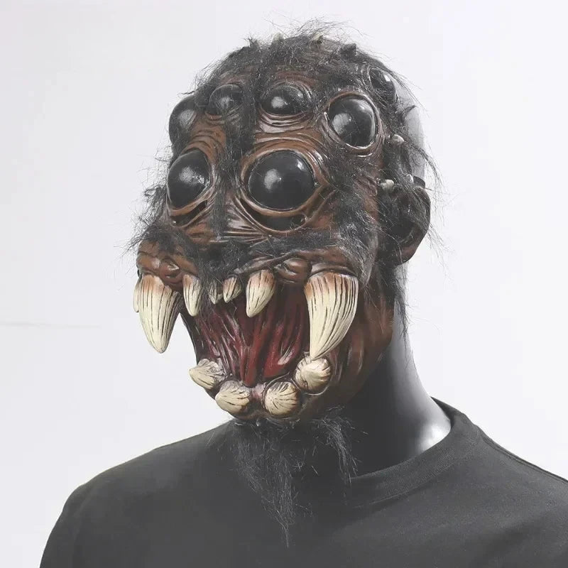 Person wearing a detailed monster mask with large eyes and sharp teeth on a plain background