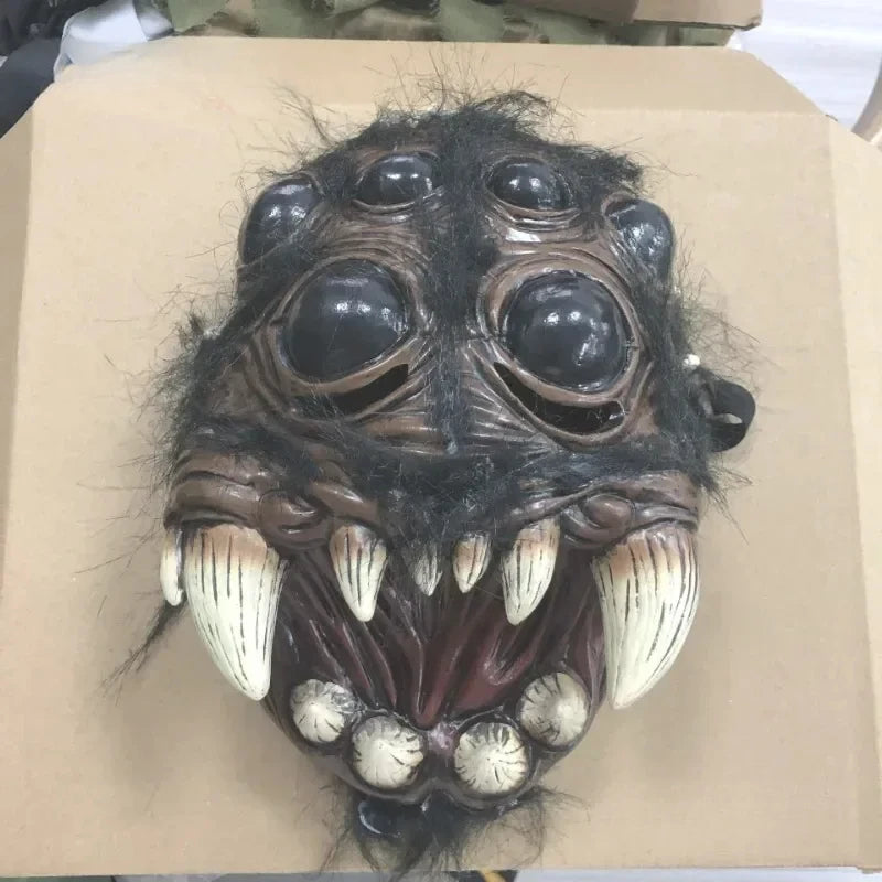 Monster mask with large eyes and sharp teeth on a cardboard surface