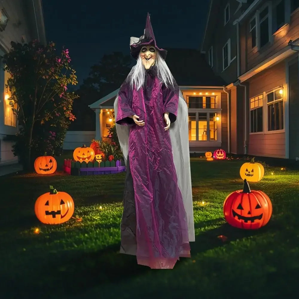 Halloween decoration of a witch figure with pumpkins in front of a house.